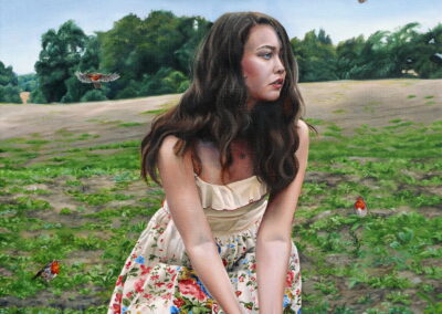 girl sitting in field holding seedling with robin birds